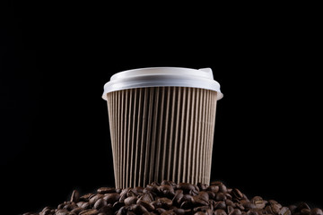 brown cardboard coffee cup, with a white lid, stands on a pile of coffee beans, concept, on a black background