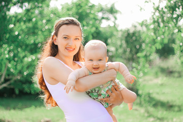 smiling mother playing with her little daughter in summer Park