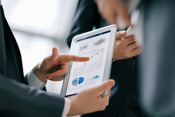 Close up of Man's hands working with digital tablet, Financial Graph charts on screen