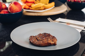 Table with appetizing fresh food barbeque meat on plate and fresh grilled vegetable fruit beverage high angle. Serving dishes ready to eating during dinner or lunch close-up