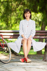 Young beautiful woman sitting on bench in park