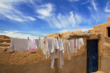 Clotheslines with white laundry on a brown loam house, under the blue sky of Marakech, Morocco.