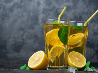 Summer lemonade Mojito with lemon and mint in glasses on a dark table