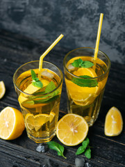 Summer lemonade Mojito with lemon and mint in glasses on a dark table
