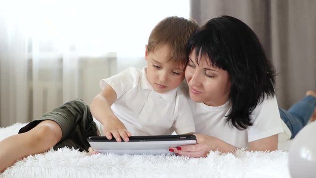 A woman and a little boy use a tablet computer to call, watch a movie and access the Internet. Dependence on gadgets.