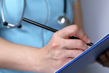 Medical exam, woman doctor or nurse with stethoscope writes a prescription paper. Concept of medicine, diagnosis, examination at the clinic, health care and assistance