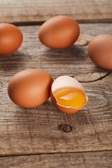 broken eggshell with yellow yolk near eggs on wooden table