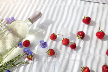 Naklejka na ściany i meble white cold wine glasses summer strawberry lying on a white table in the sun