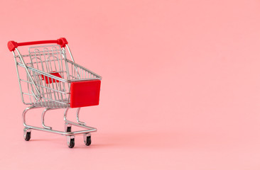 Empty shopping cart on colored background. Close-up of shopping trolley on with some copy space. Consumer concept. Online shopping concept. Black Friday and Cyber Monday 