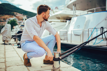 Young handsome man preparing boat to start a journey at the pier