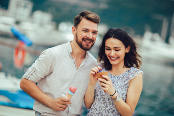 Happy couple having date and eating ice cream on vacation. Sea background.