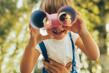 Closeup image of cute little boy playing with a binoculars searching for an imagination or...