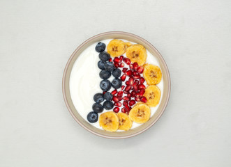 Breakfast smoothie bowl. Smoothie bowl with fresh kiwi, blueberry, pomegranate, granola, banana and yogurt. Grey background.  