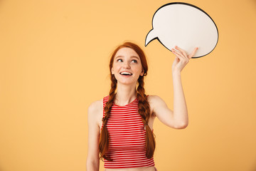 Dreaming  young beautiful redhead woman posing isolated over yellow background holding speech bubble.