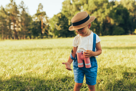 Image of cute little boy playing with a binoculars searching for an imagination or exploration in summer day in park. Happy child playing game outdoors in the forest. Childhood concept