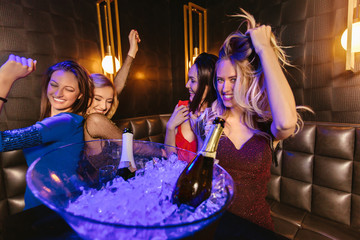 Happy women clinking champagne glasses and celebrating at night club