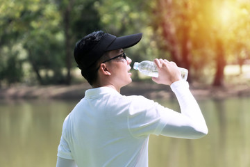 Golfer man drinking of fresh water with bottle while thirsty and tired. Young men wearing black hat...