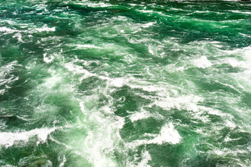 Background made from a rushing, foamy river in a beautiful turquoise and green color.