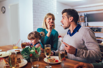 Happy family having meal in kitchen at home