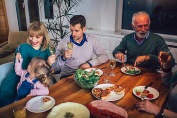 Multi generation family enjoying meal around table at home