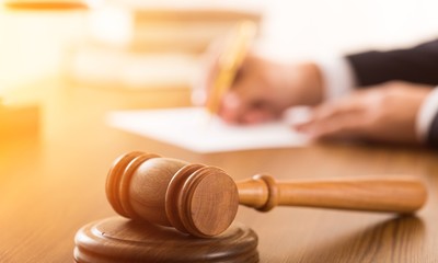 Closeup of Gavel with Lawyer Writing on Background