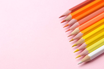 Multicolored pencils in yellow tones on a gentle trendy pink background. place for text.