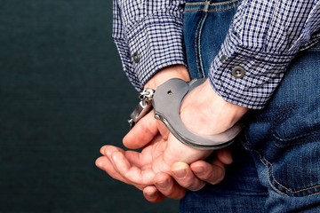 Cropped image of male hands in handcuffs behind his back