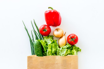 Buying fresh vegetables in paper bag on white background top view