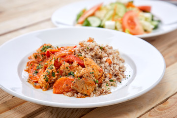 meat with buckwheat and salad on the wooden background