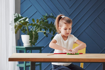 Children playing with colored plasticine on the wooden table at home