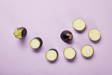 top view of ripe sliced eggplant on violet background with copy space