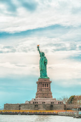 Fototapeta na wymiar New York City Statue Of Liberty on Liberty Island Against Cloudy Blue Sky Background. Copy Space, Patriotism, Travel Concept. Vertical Banner