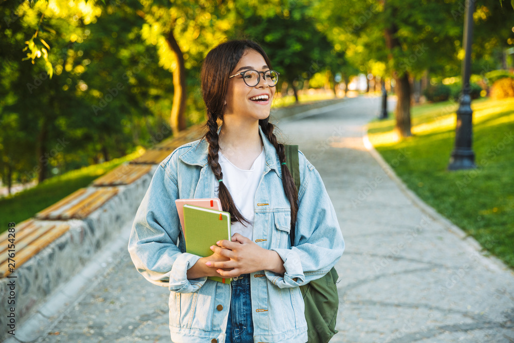 Poster happy young teenage student girl carrying backpack