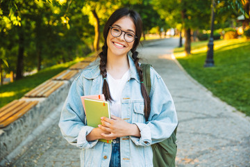 Happy young teenage student girl carrying backpack