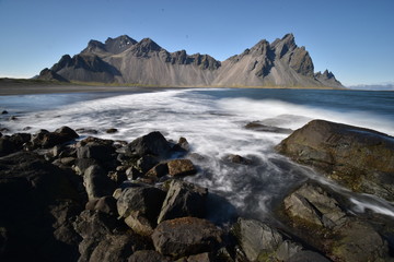 Beautiful view of the Vestrahorn Mountains with black sand and the ocean in front near Höfn in Iceland