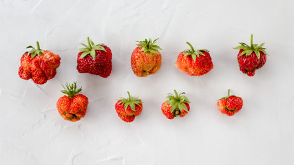 trendy ugly berries on a light table. Unusual strawberries. Natural organic food. Top view, copy space. horizontal orientation