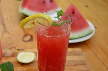 Colorful tropical fresh watermelon smoothie summer drinks in the glasses on wood table background. Refreshing watermelon coсtail with slimon of green foliage. The concept of leisure, travel