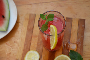 Colorful tropical fresh watermelon smoothie summer drinks in the glasses on wood table background. Refreshing watermelon coсtail with slimon of green foliage. The concept of leisure, travel