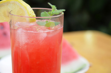 Colorful tropical fresh watermelon smoothie summer drinks in the glasses on wood table background. Refreshing watermelon coсtail with slimon of green foliage. The concept of leisure, travel