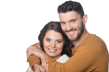 Portrait of happy young couple smiling and hugging on white background