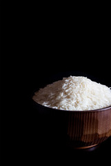 Rice in a wooden bowl on a black background