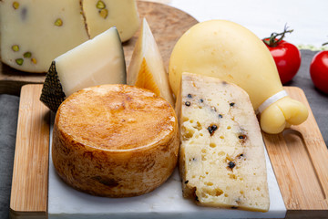 Variety of Italian pecorino and provolone cheeses, yellow aged, with black peppers from Nebrodi, white Il Palio and black molarotto, close up