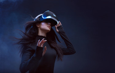 Beautiful woman with flowing hair in futuristic dress over dark background. Girl in glasses of...
