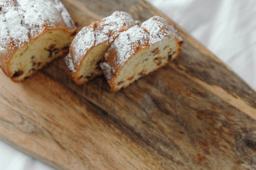 Raisin cake, dusted with icing sugar. Cupcake with raisins on a wooden board.