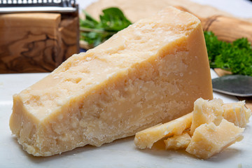 One piece of Italian original aged Parmesan cheese on white marble board close up