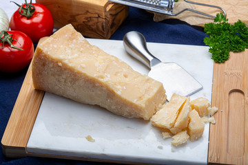 One piece of Italian original aged Parmesan cheese on white marble board close up