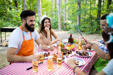 Group of happy friends eating and drinking beers at barbecue dinner
