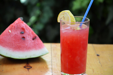 Colorful tropical fresh watermelon smoothie summer drinks in the glasses on wood table background. Refreshing watermelon coсtail with slimon of green foliage. The concept of leisure, travel