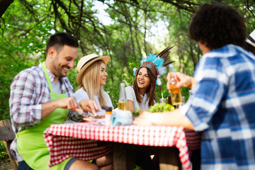 Happy friends camping and having a barbecue in nature