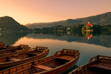 wooden boats at lake bled on a pier in summer during sunrise sunset